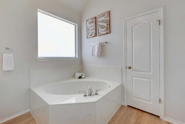 bathroom with a bath, vaulted ceiling, and hardwood / wood-style floors