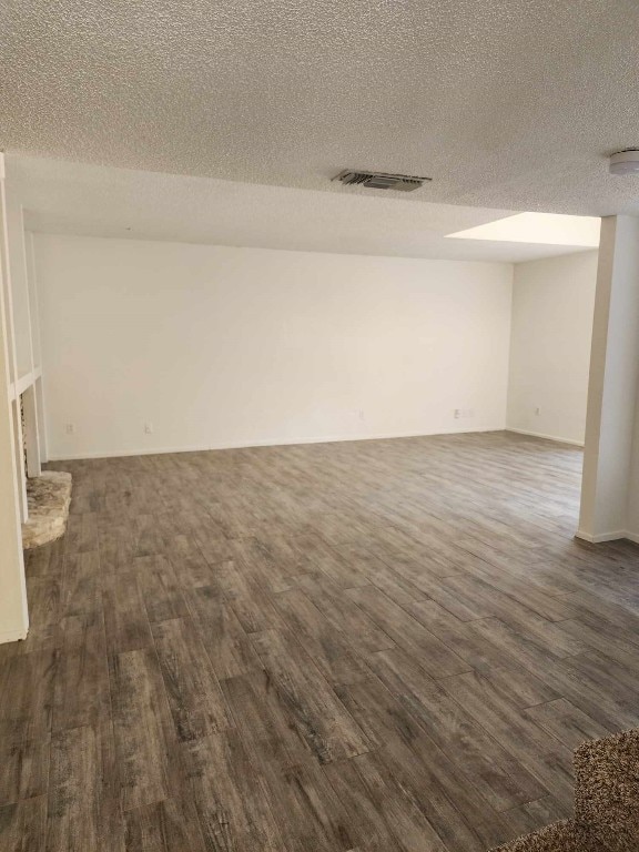 spare room with a textured ceiling and dark hardwood / wood-style flooring