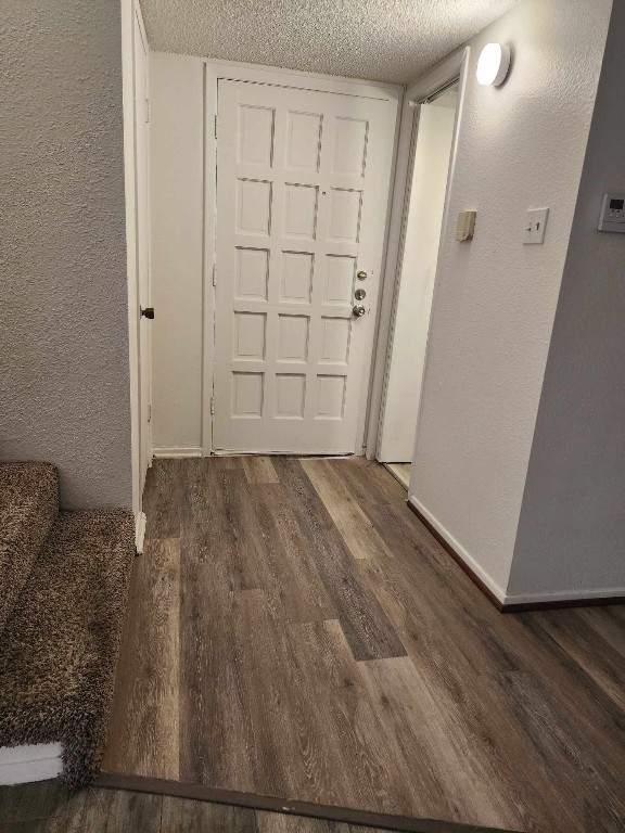 corridor with dark wood-type flooring and a textured ceiling