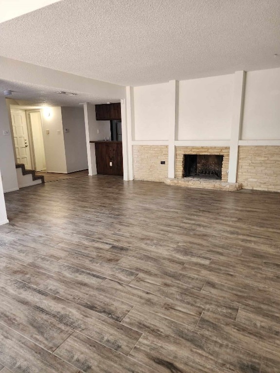 unfurnished living room featuring dark wood-type flooring and a textured ceiling