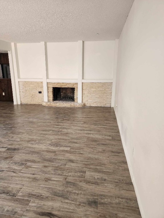 unfurnished living room with a textured ceiling and dark hardwood / wood-style floors