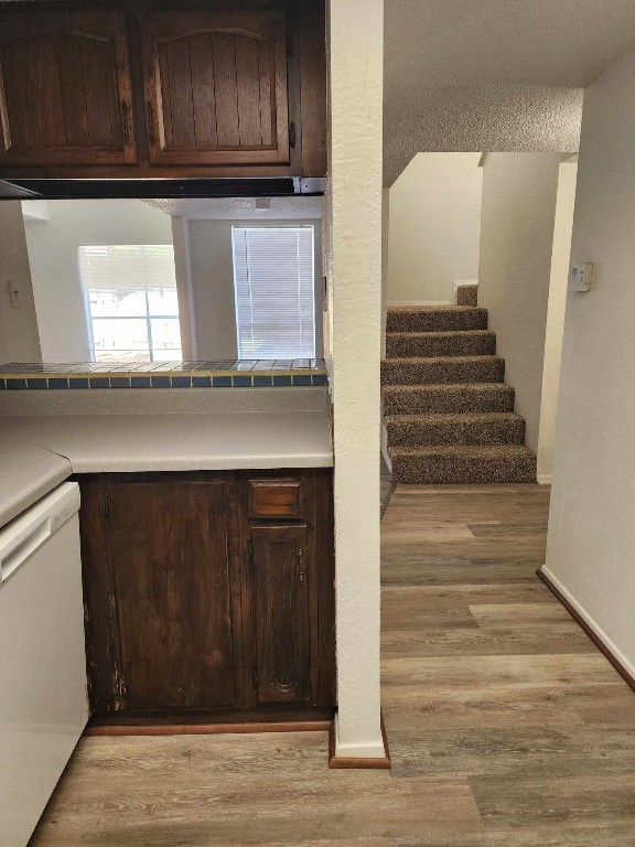 kitchen with dishwasher, dark brown cabinets, and light wood-type flooring