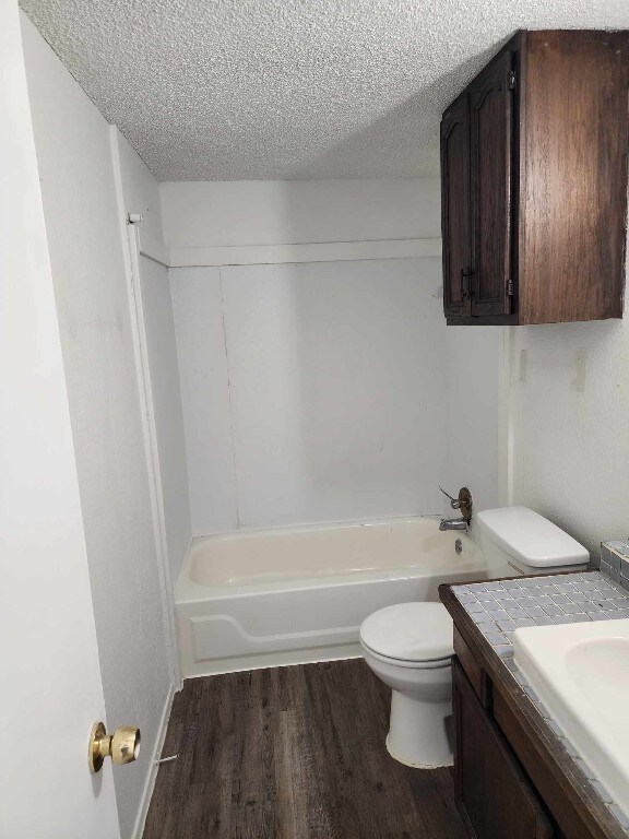 full bathroom featuring a textured ceiling, toilet, shower / tub combination, vanity, and hardwood / wood-style flooring