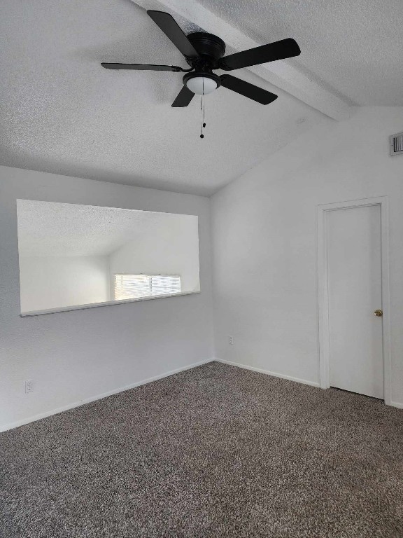 unfurnished room with ceiling fan, vaulted ceiling with beams, a textured ceiling, and carpet flooring