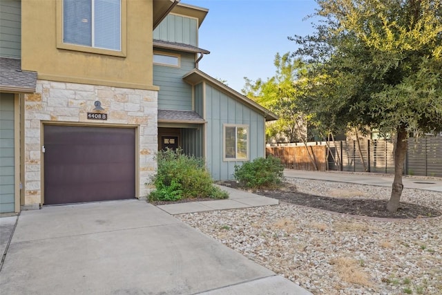 4408 Banister Ln Unit B, Austin, TX 78745 - doorway to property featuring driveway, stone siding, board and batten siding, an attached garage, and fence