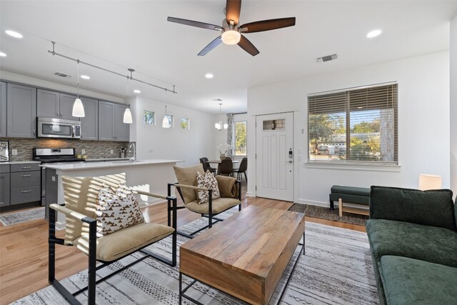 living room featuring light hardwood / wood-style flooring, rail lighting, and ceiling fan