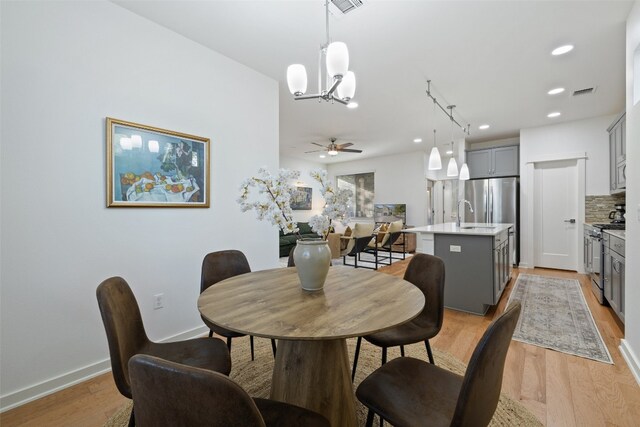 dining area with light hardwood / wood-style flooring and ceiling fan with notable chandelier