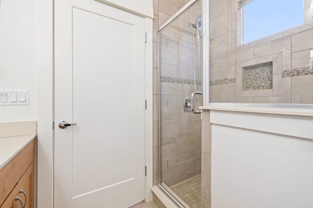 bathroom featuring a shower with door and vanity