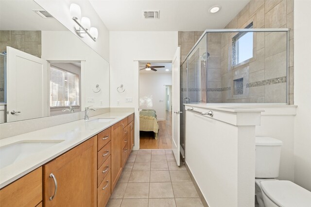 bathroom featuring a shower with door, tile patterned floors, toilet, vanity, and ceiling fan