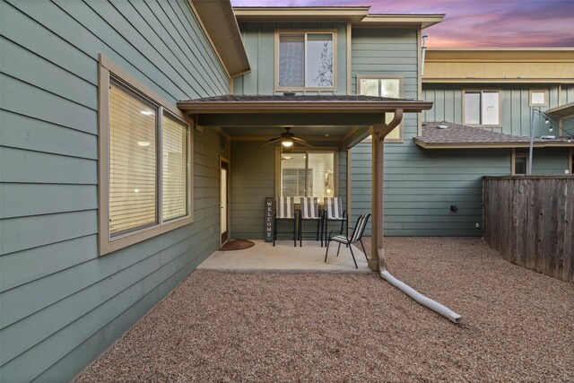 back house at dusk with ceiling fan and a patio area