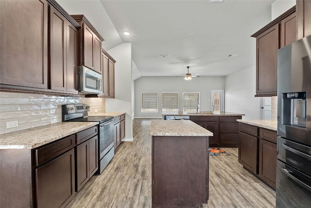 kitchen with appliances with stainless steel finishes, sink, a kitchen island, backsplash, and light hardwood / wood-style floors