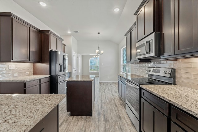 kitchen featuring a kitchen island, appliances with stainless steel finishes, vaulted ceiling, light hardwood / wood-style floors, and light stone counters