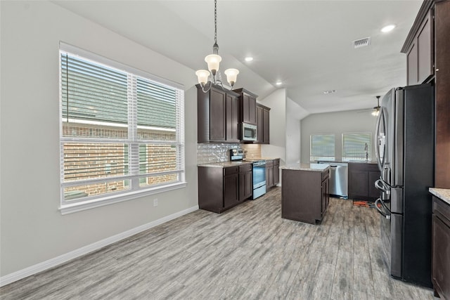 kitchen featuring stainless steel appliances, lofted ceiling, a center island, and plenty of natural light