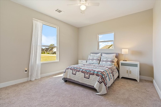 bedroom with ceiling fan, multiple windows, and light colored carpet