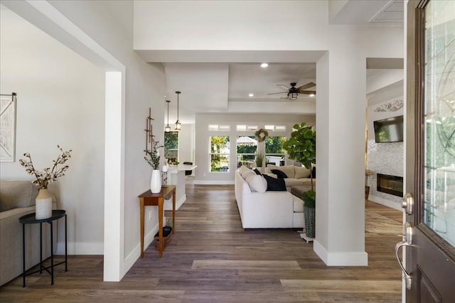 foyer with dark wood-type flooring, a fireplace, and ceiling fan