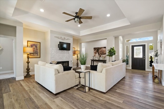 living room featuring light hardwood / wood-style floors, a tray ceiling, and ceiling fan