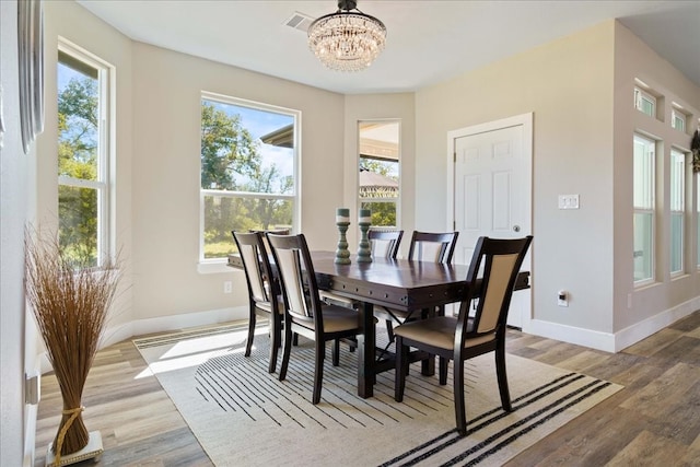 dining room with light hardwood / wood-style flooring and a notable chandelier