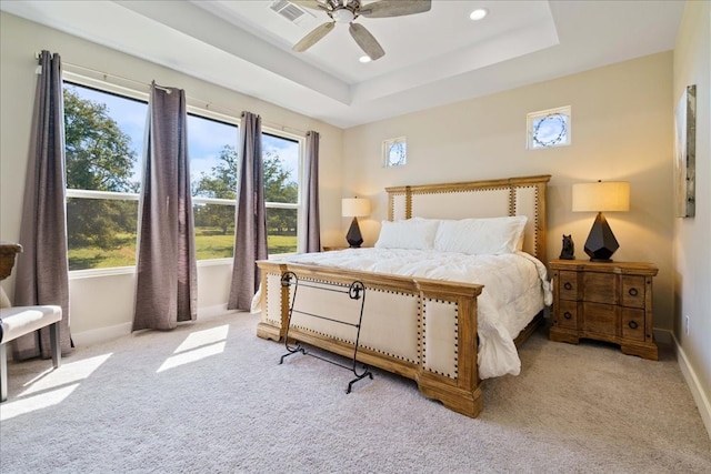 carpeted bedroom featuring multiple windows, a tray ceiling, and ceiling fan