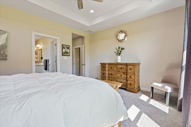 bedroom with carpet floors, connected bathroom, a raised ceiling, and ceiling fan