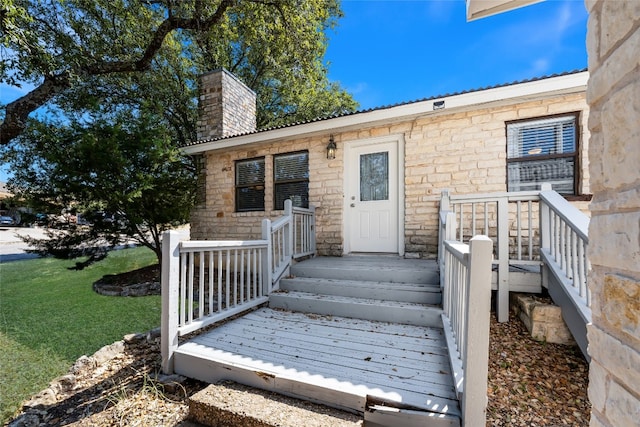 property entrance featuring a yard and a wooden deck