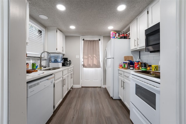 kitchen with white cabinets, a textured ceiling, hardwood / wood-style flooring, sink, and white appliances