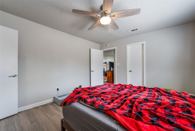 bedroom featuring ceiling fan, a textured ceiling, and light wood-type flooring