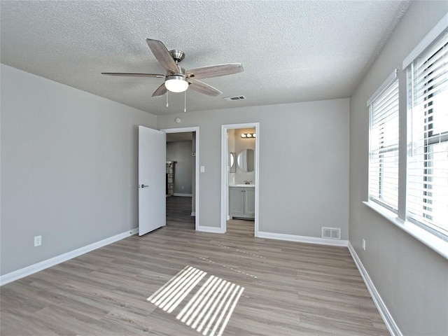 21401 Patton Ave Unit A & B, Lago Vista, TX 78645 - unfurnished bedroom with a textured ceiling, wood finished floors, ensuite bathroom, baseboards, and ceiling fan