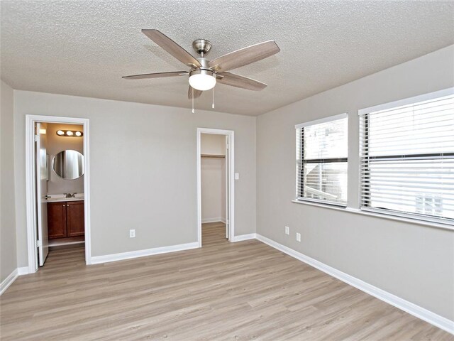21401 Patton Ave Unit A & B, Lago Vista, TX 78645 - unfurnished bedroom featuring light wood-type flooring, a textured ceiling, a spacious closet, and baseboards