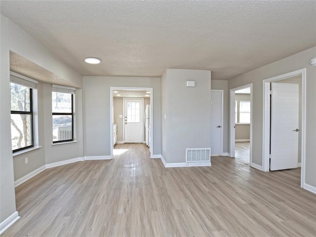 21401 Patton Ave Unit A & B, Lago Vista, TX 78645 - empty room featuring a textured ceiling, light wood-type flooring, healthy amount of natural light, and baseboards