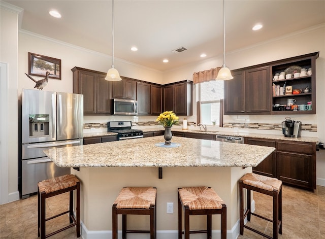 kitchen with stainless steel appliances, a center island, decorative light fixtures, and a kitchen breakfast bar