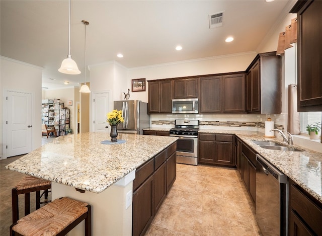 kitchen with a breakfast bar area, hanging light fixtures, sink, a center island, and appliances with stainless steel finishes