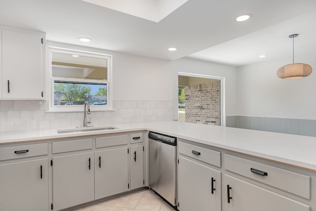 kitchen with backsplash, sink, pendant lighting, stainless steel dishwasher, and white cabinets