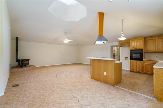 kitchen featuring a wood stove, ceiling fan, hanging light fixtures, oven, and light tile patterned flooring