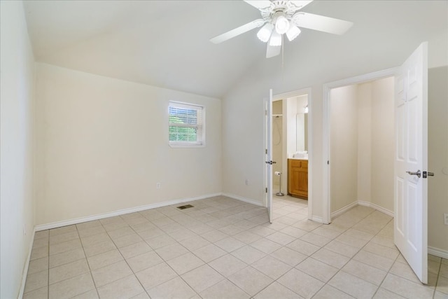 unfurnished bedroom with ceiling fan, light tile patterned flooring, connected bathroom, and vaulted ceiling