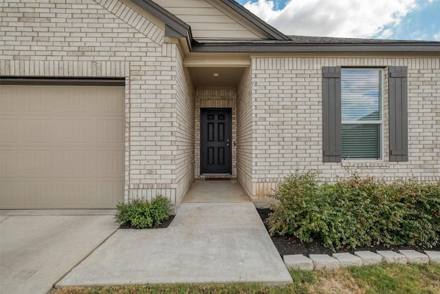 doorway to property with an attached garage and brick siding