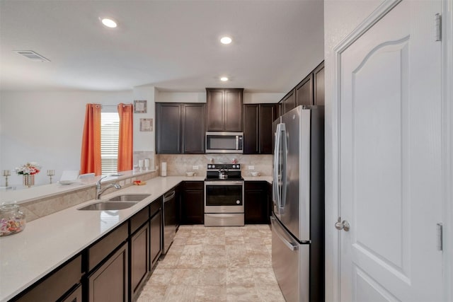 kitchen with dark brown cabinetry, tasteful backsplash, stainless steel appliances, light countertops, and a sink