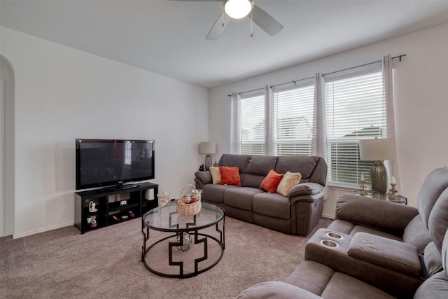 carpeted living area featuring arched walkways and ceiling fan