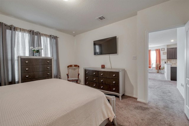 bedroom with baseboards, visible vents, and light colored carpet