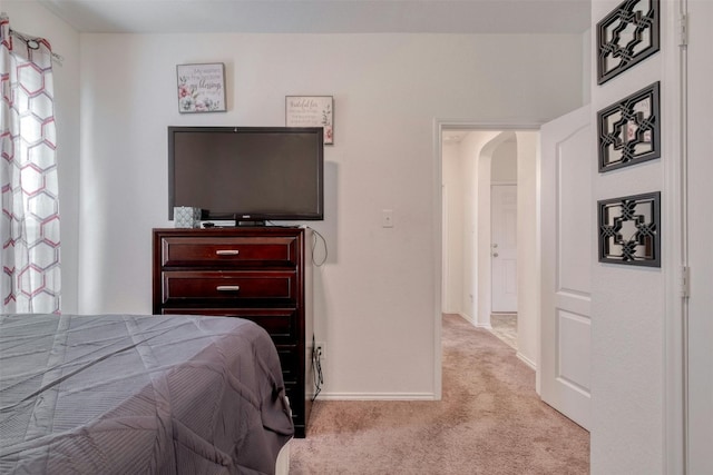 carpeted bedroom featuring arched walkways and baseboards