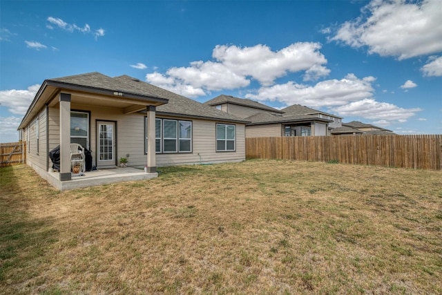 back of house with a fenced backyard, a lawn, and a patio