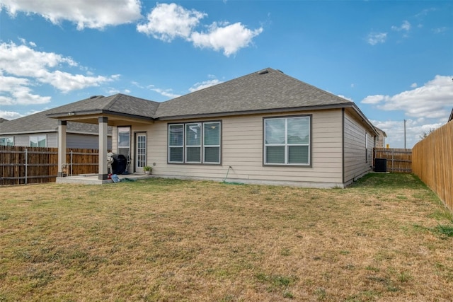 rear view of house featuring a fenced backyard, a shingled roof, cooling unit, and a lawn