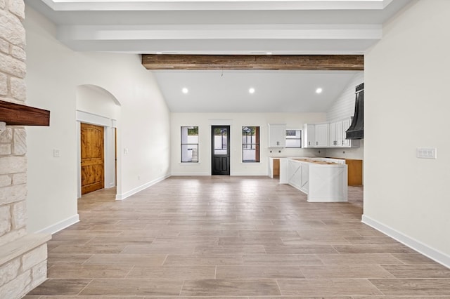 interior space featuring vaulted ceiling with beams and light wood-type flooring