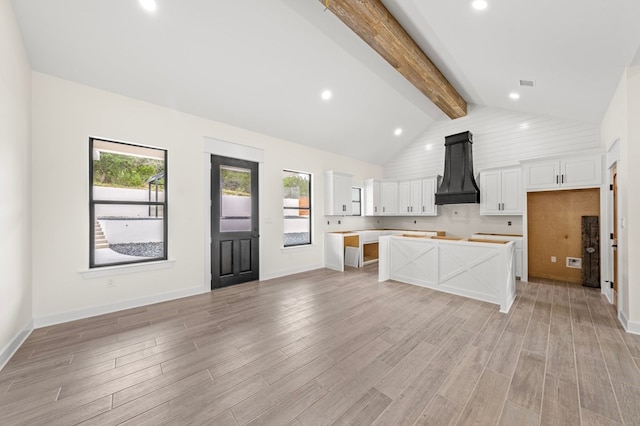 kitchen featuring beam ceiling, custom exhaust hood, light hardwood / wood-style floors, and white cabinets