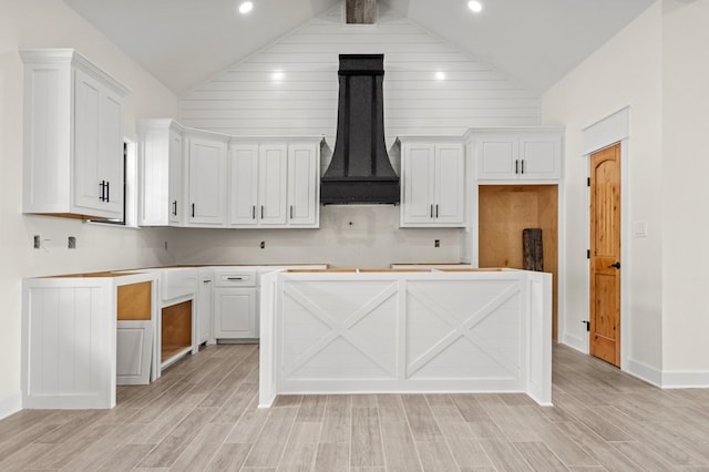 kitchen with light hardwood / wood-style floors, vaulted ceiling, custom exhaust hood, and white cabinets