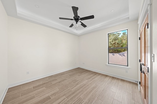 unfurnished room with ceiling fan, a raised ceiling, and light hardwood / wood-style flooring