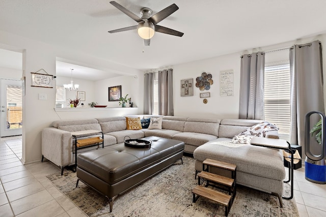 tiled living room featuring ceiling fan with notable chandelier