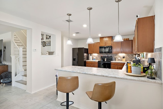 kitchen with black appliances, kitchen peninsula, decorative light fixtures, decorative backsplash, and light tile patterned floors