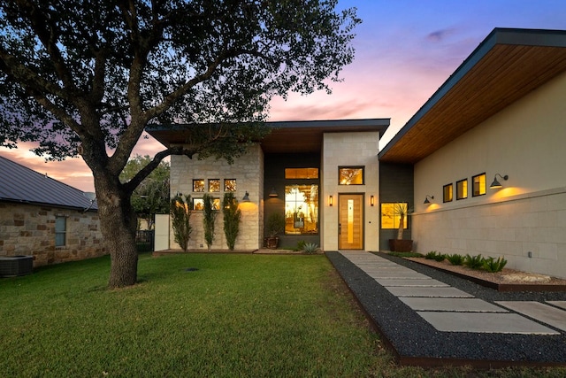 exterior entry at dusk with a yard and central air condition unit