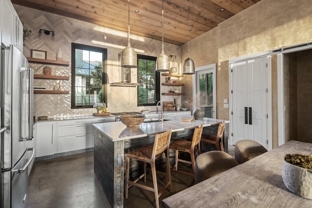 kitchen with high end refrigerator, wood ceiling, a kitchen island with sink, white cabinetry, and hanging light fixtures