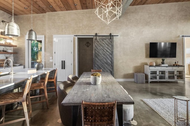 dining room featuring a barn door, wood ceiling, and a towering ceiling